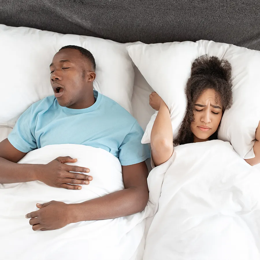 Annoyed Woman Covering Ears From Man's Snoring