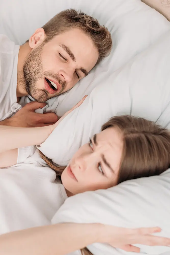 Annoyed Woman Next To Snoring Man in Bed