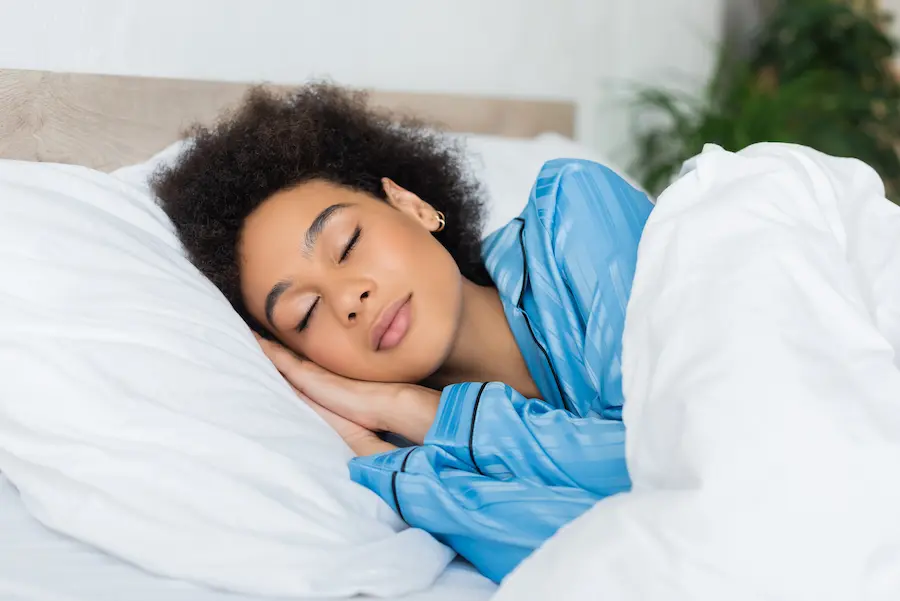Woman Relaxing Peacefully in Bed Wearing Pajamas
